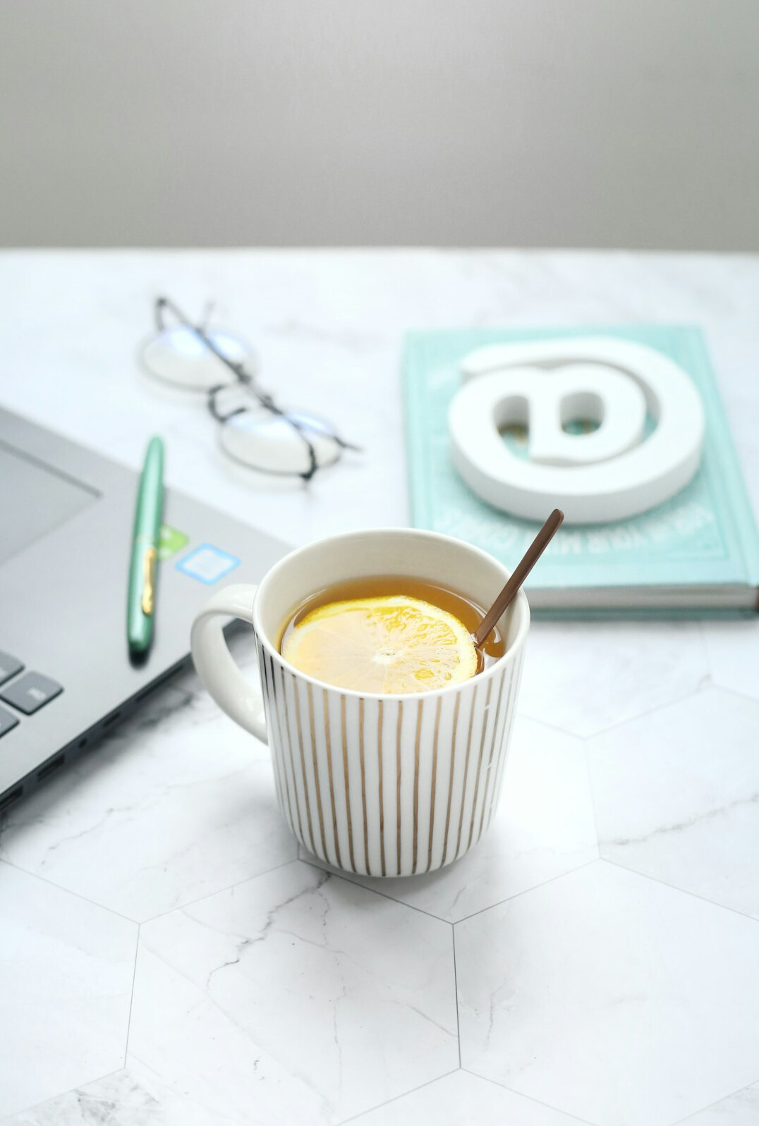 Laptop and notebook on a bright desk with a cup of coffee